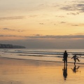 Promeneurs sur la plage d'Ault au soleil couchant