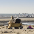 Deux dames assises dans un chariot qui leur sert de banc sur la plage de Quend regardent les chars-à-voile