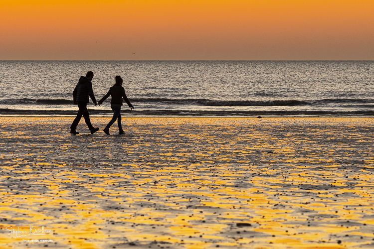 Couple sur la plage au soleil couchant